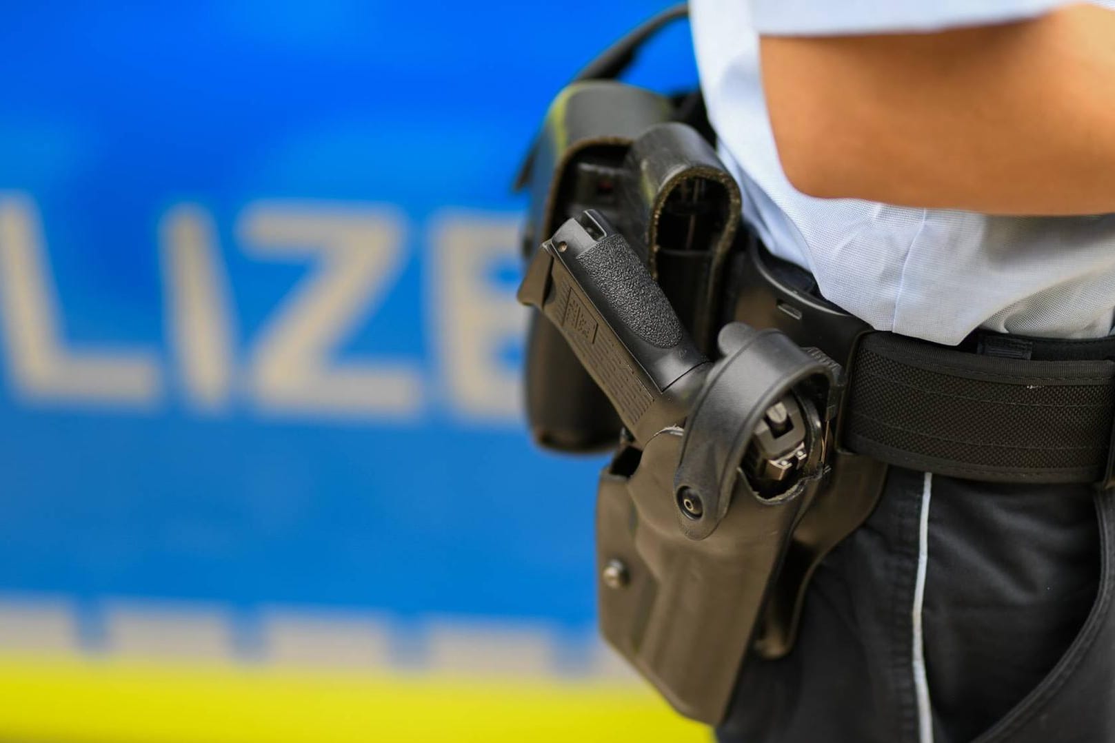 Ein Polizist steht vor einem Streifenwagen