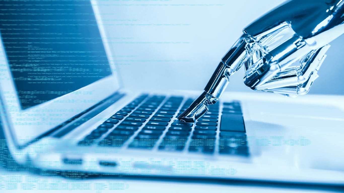 Eine Roboter-Hand tippt eine Taste auf einem Laptop: Die vollmundigen KI-Versprechen der Industrie basieren nicht auf Fakten.