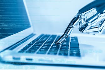 Eine Roboter-Hand tippt eine Taste auf einem Laptop: Die vollmundigen KI-Versprechen der Industrie basieren nicht auf Fakten.