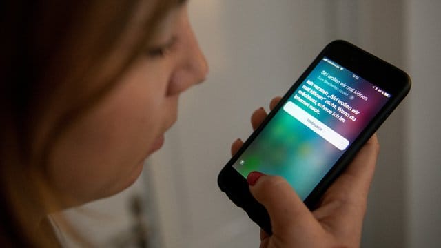 Eine junge Frau bedient auf einem iPhone die Spracherkennung des Apple-Programms Siri. Eine junge Frau bedient auf einem iPhone die Spracherkennung des Apple-Programms Siri.