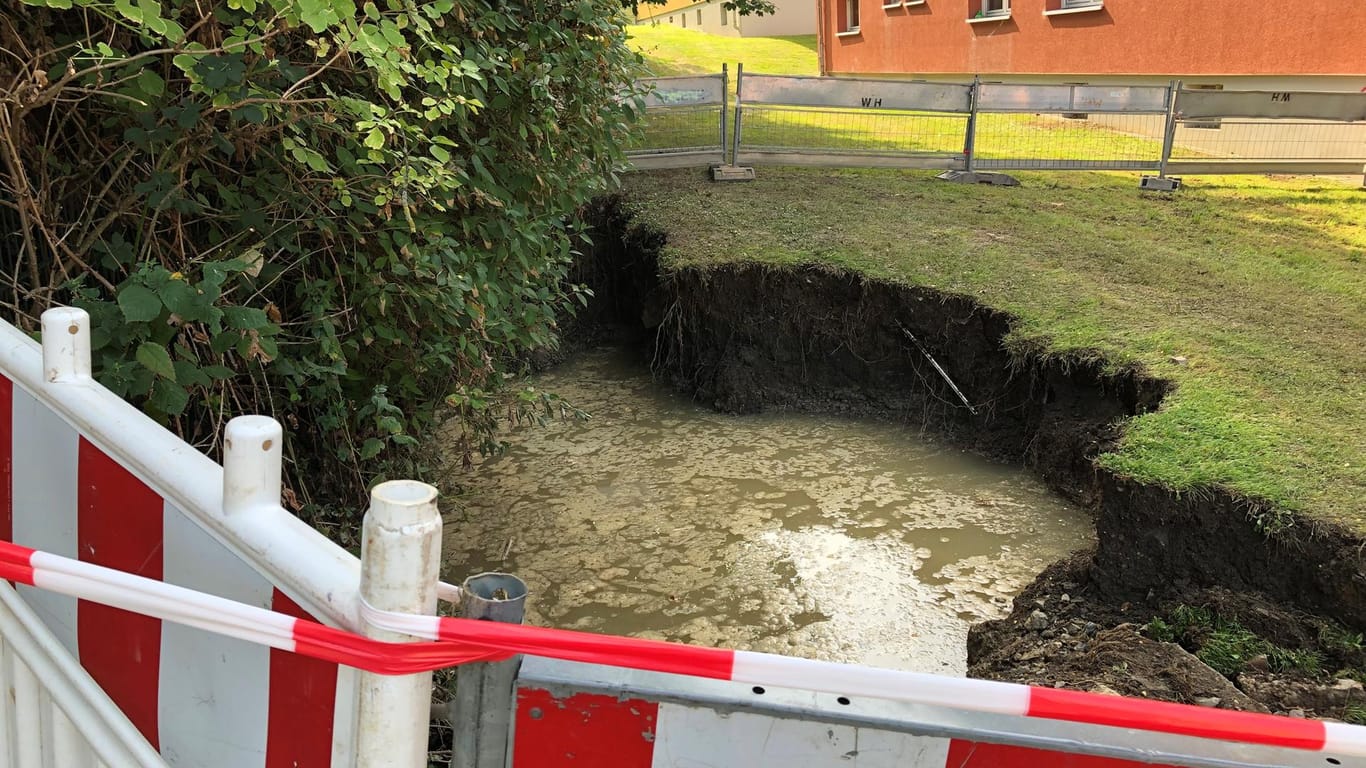 Ein abgesperrtes Loch in einer Wiese: In Hagen hat das Wasser Schäden hinterlassen.