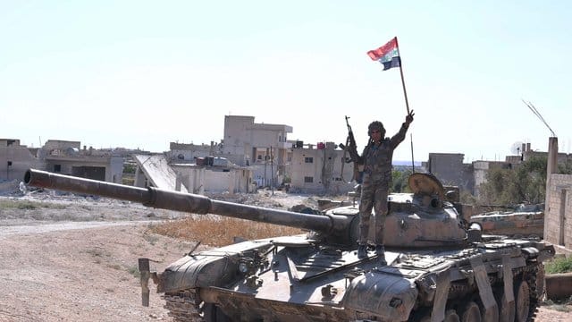 Ein syrischer Soldat zeigt auf einem Panzer das Victory-Zeichen. Ein syrischer Soldat zeigt auf einem Panzer das Victory-Zeichen.