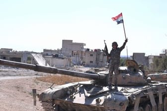Ein syrischer Soldat zeigt auf einem Panzer das Victory-Zeichen.