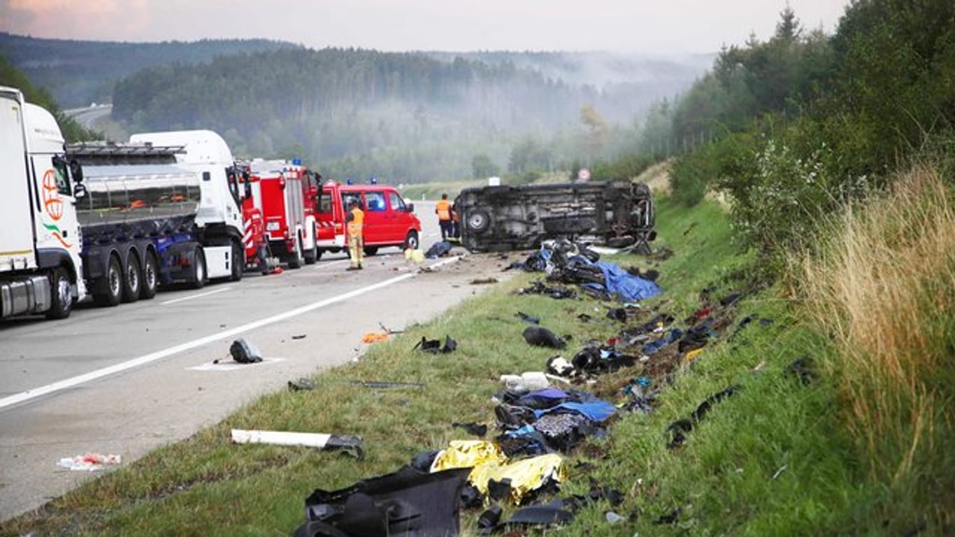 Trümmerteile liegen an der Unfallstelle neben der Autobahn 9, im Hintergrund liegt der umgestürzte Transporter.