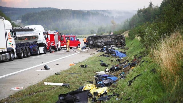 Trümmerteile liegen an der Unfallstelle neben der Autobahn 9, im Hintergrund liegt der umgestürzte Transporter.