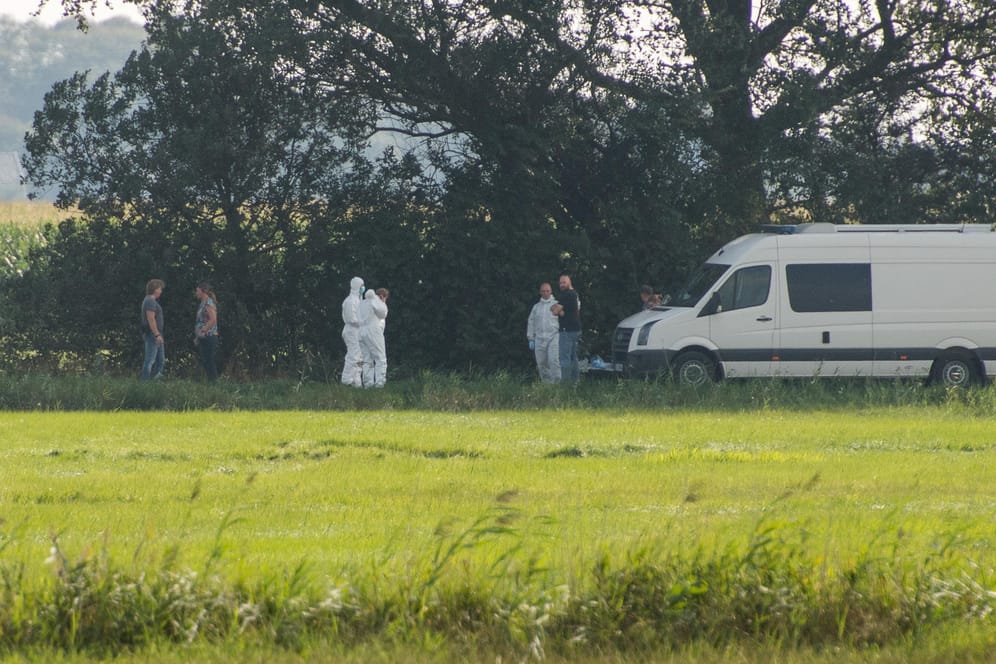 Stadum in Schleswig-Holstein: Ermittler in weißen Schutzanzügen stehen während eines Polizeieinsatzes im Zusammenhang mit der vermissten 23-jährigen Nathalie M. aus Nordfriesland neben einem Polizeifahrzeug.