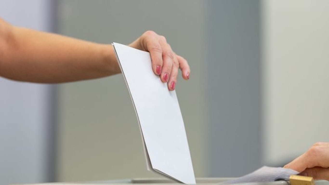 Eine Wählerin wirft bei der Stimmabgabe zur Landtagswahl in Sachsen ihren Wahlzettel in eine Wahlurne.
