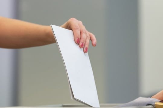 Eine Wählerin wirft bei der Stimmabgabe zur Landtagswahl in Sachsen ihren Wahlzettel in eine Wahlurne.