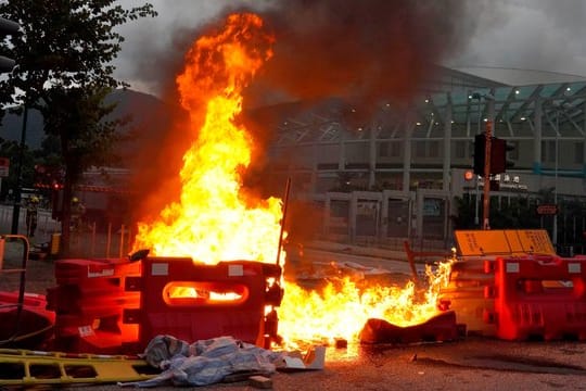 Von prodemokratischen Demonstranten vor dem Flughafen errichtete Barrikaden stehen in Flammen.