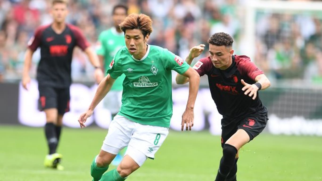 Werders Yuya Osako (l) setzt sich gegen Augsburgs Ruben Vargas durch.