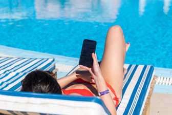 Eine Frau liegt am Pool: In einigen Unternehmen ist festgelegt, dass mit längerer Betriebszugehörigkeit ein längerer Urlaubsanspruch entsteht. (Symbolbild)