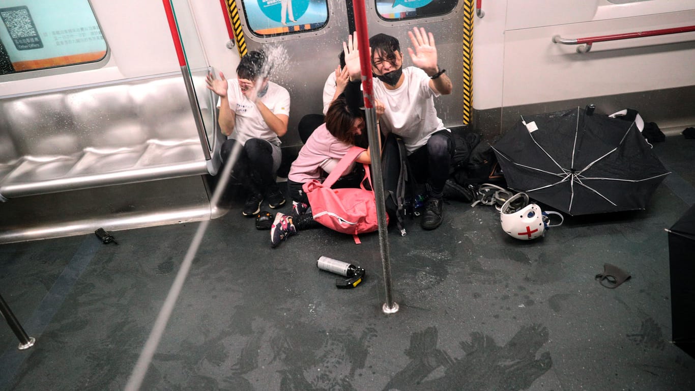 Demonstranten werden von Polizisten mit Pfefferspray besprüht, während sie in einem Zugabteil sitzen.