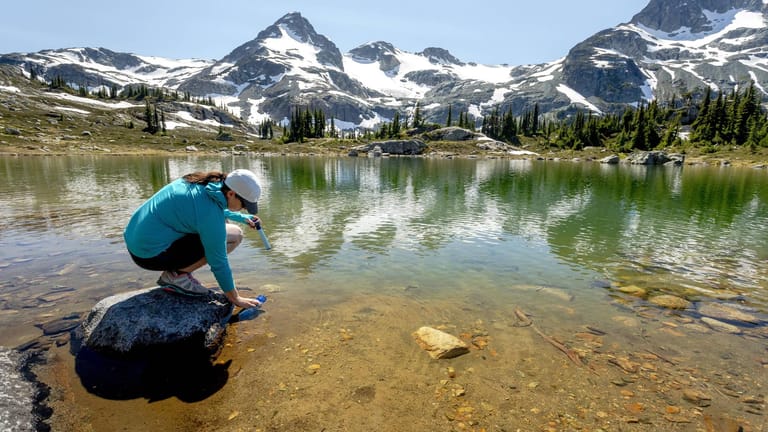 Eine Frau füllt Wasser vom See in eine Flasche: Die Natur in British Columbia ist nahezu unberührt.