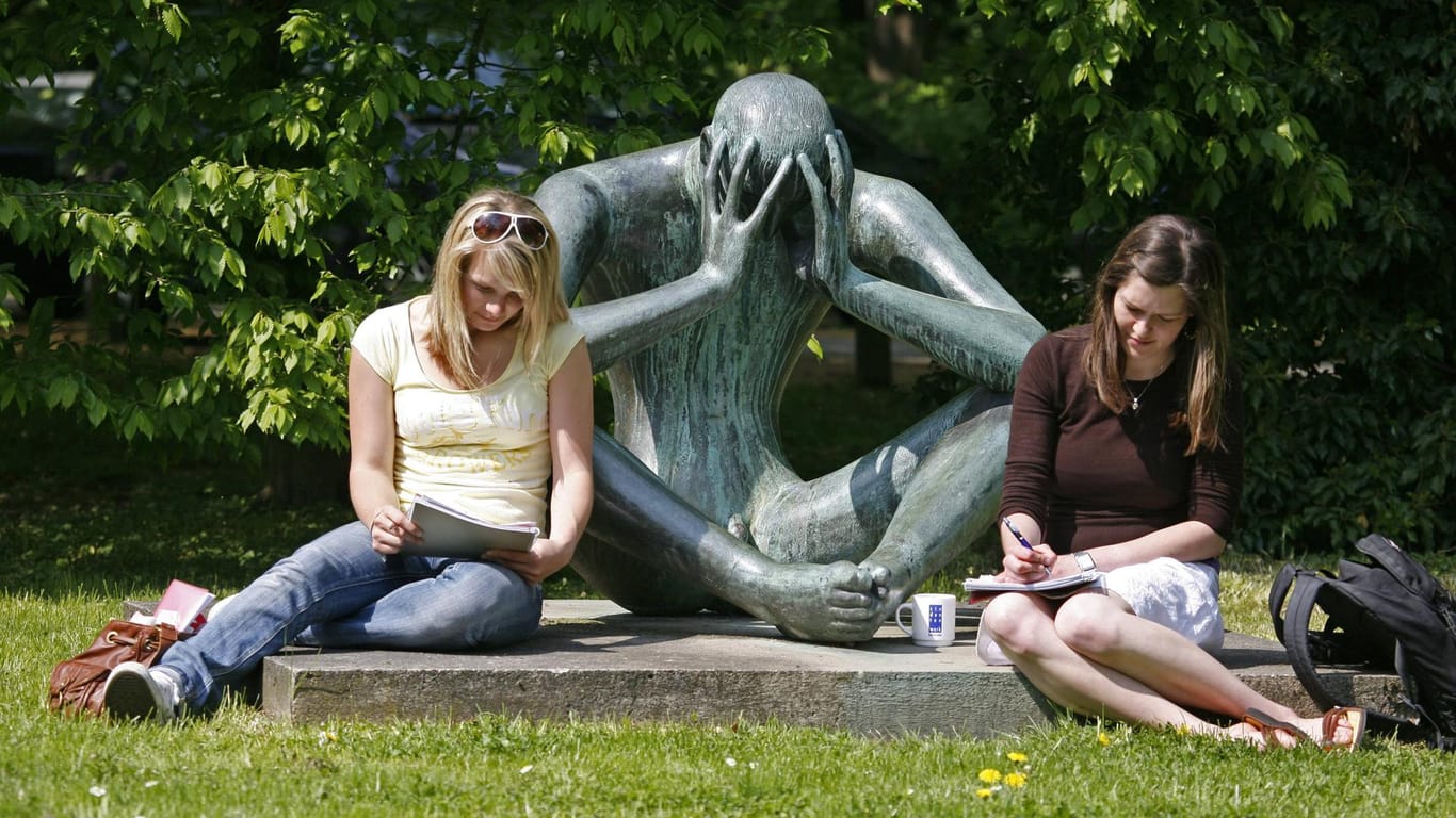 Zwei Studentinnen sitzen vor einer Skulptur auf dem Gelände der Universität Karlsruhe: Wohnraum für Studierende ist hier knapp.