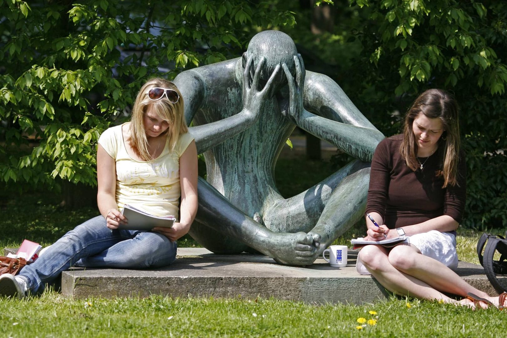 Zwei Studentinnen sitzen vor einer Skulptur auf dem Gelände der Universität Karlsruhe: Wohnraum für Studierende ist hier knapp.