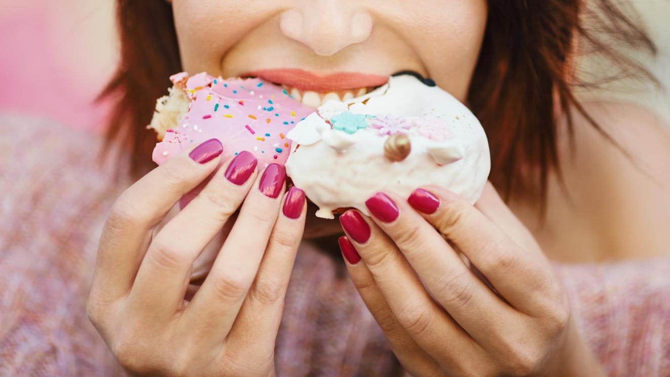Eine Frau beißt in ein Dessert: Wer an einem Tag richtig zulang, sollte die Woche zuvor weniger Kalorien zu sich genommen haben, um nicht zuzunehmen.