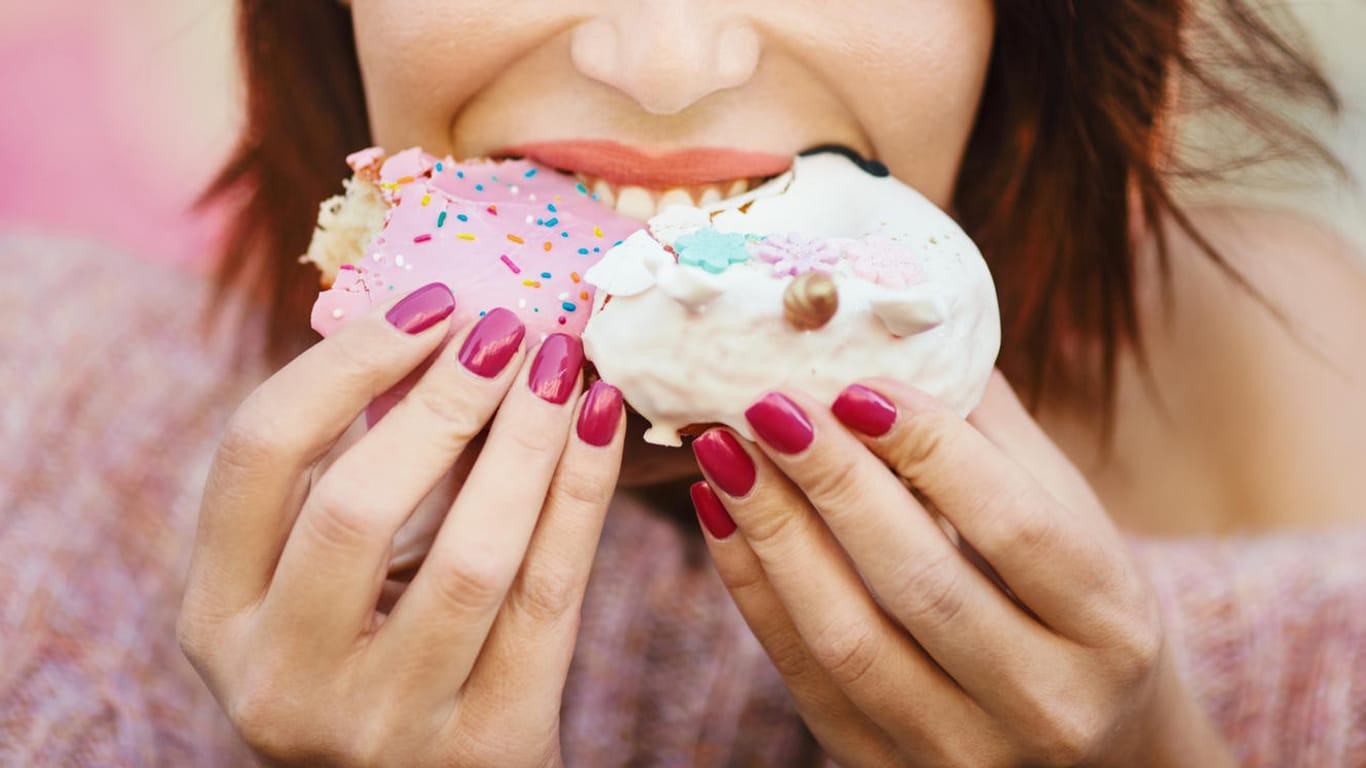 Eine Frau beißt in ein Dessert: Wer an einem Tag richtig zulang, sollte die Woche zuvor weniger Kalorien zu sich genommen haben, um nicht zuzunehmen.