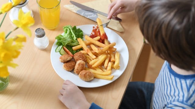 Ein Junge sitzt vor einem Teller mit Chicken Nuggets und Pommes Frites (Archiv). Ein Junge sitzt vor einem Teller mit Chicken Nuggets und Pommes Frites (Archiv).