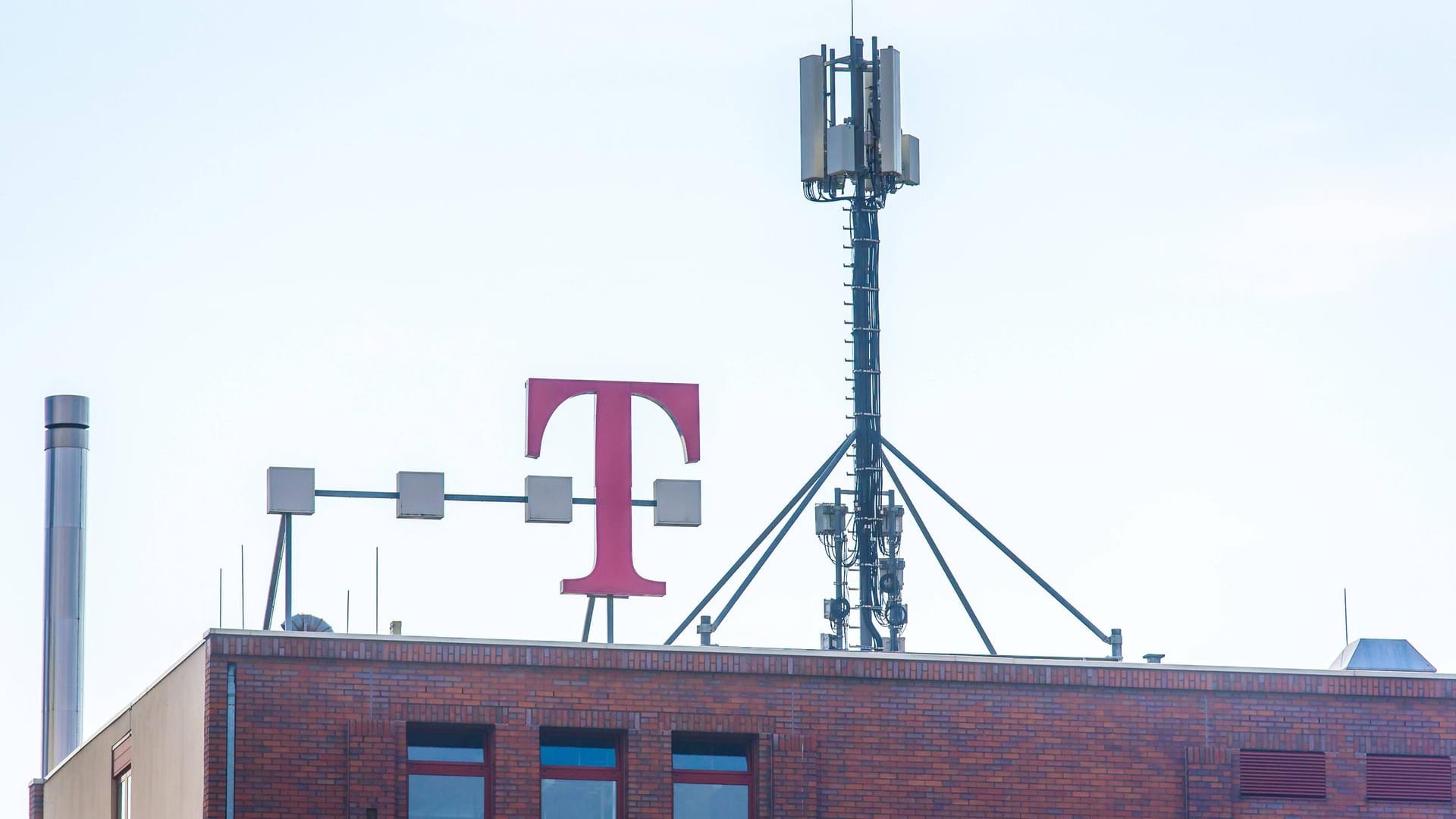 Ein Mobilfunkmast steht auf einem Gebäude mit dem Telekom-Logo: Die ersten 5G-Frequenzen wurden zugeteilt.