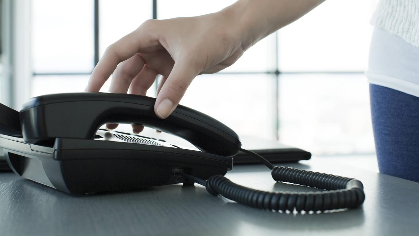 Eine Frau nimmt einen Telefonhörer ab: In Essen zocken vermehrt falsche Polizisten vor allem Ältere am Telefon ab. (Symbolbild)