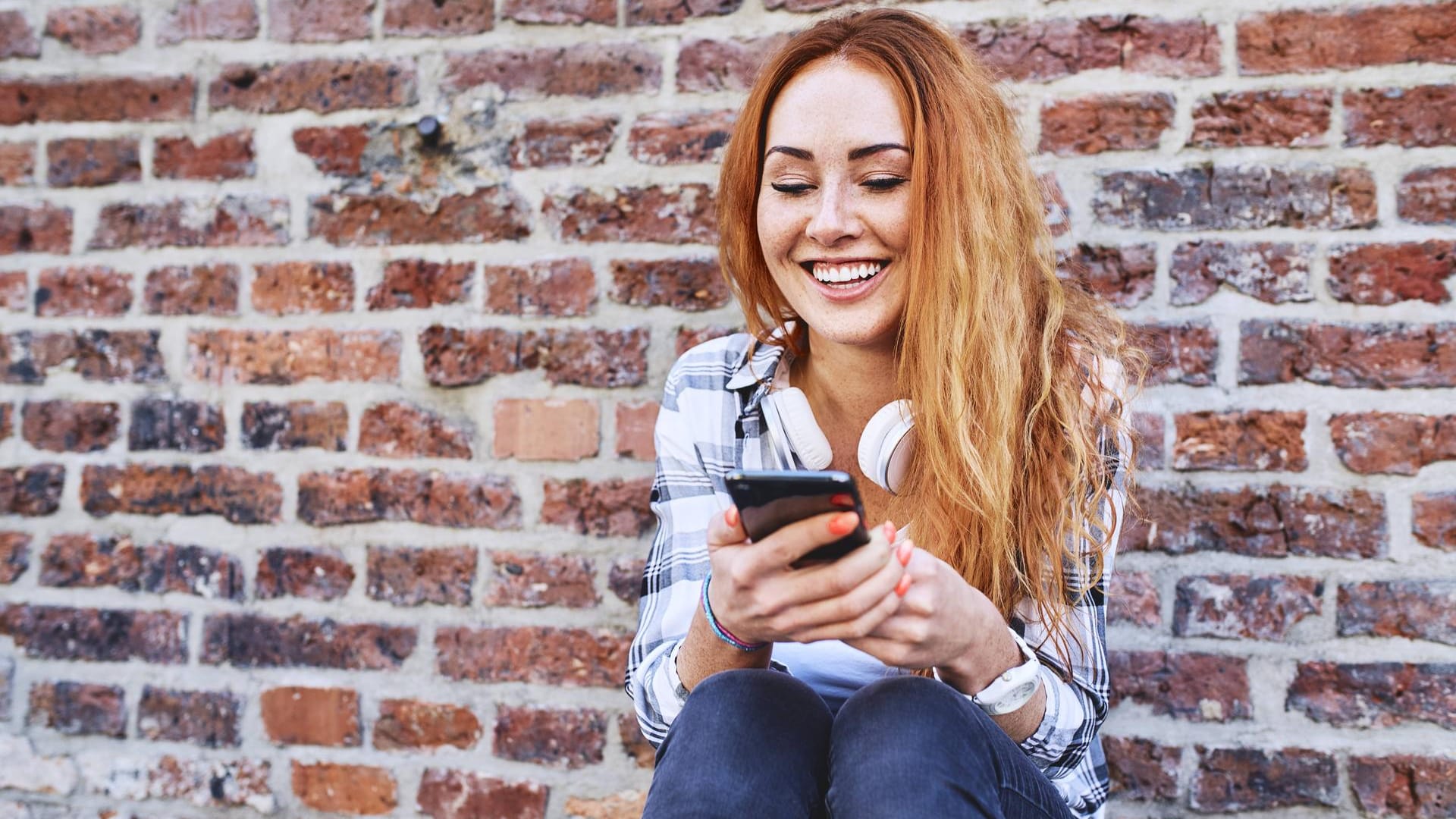 Eine junge Frau nutzt ihr Smartphone: Viele Nutzer schrecken davor zurück, ein gebrauchtes Smartphone zu kaufen. Dabei lässt sich dabei viel Geld sparen.