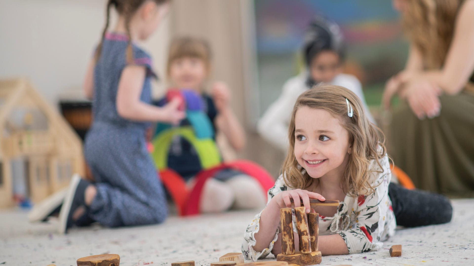 Eine Schülerin spielt mit Holz auf dem Boden: Selber tun, eigene Erfahrungen machen, um sie dann zu gestalten und denkend zu verarbeiten steht in Waldorfschulen im Vordergrund.