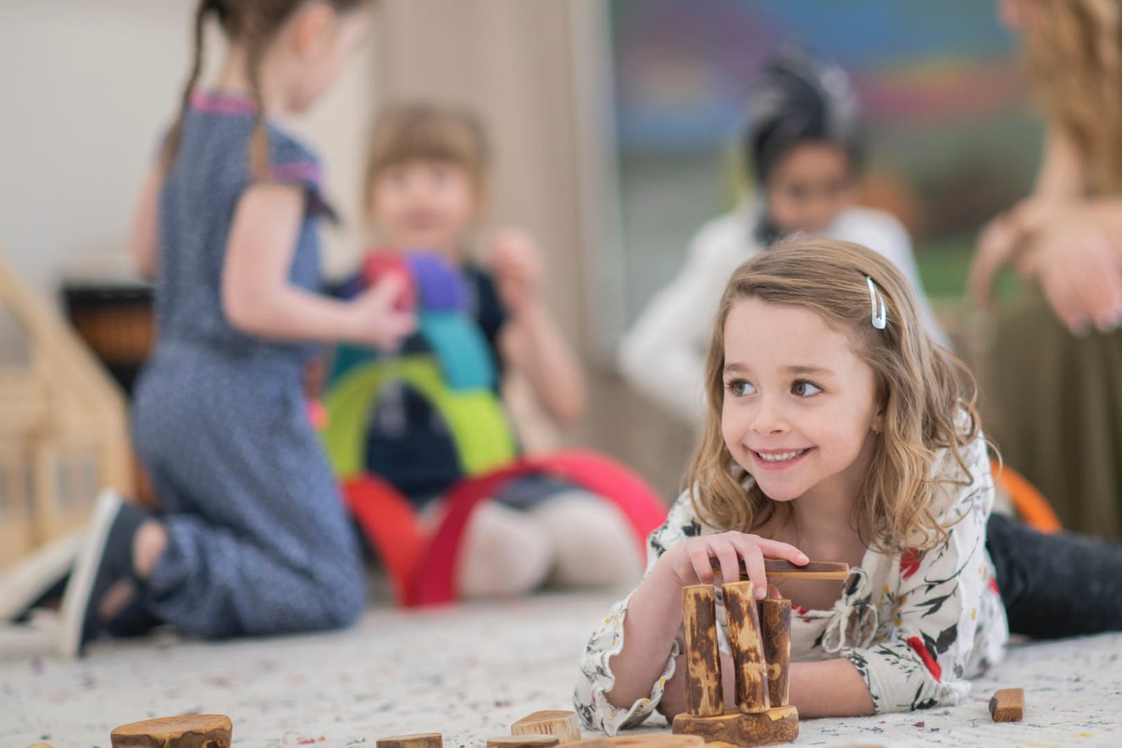 Eine Schülerin spielt mit Holz auf dem Boden: Selber tun, eigene Erfahrungen machen, um sie dann zu gestalten und denkend zu verarbeiten steht in Waldorfschulen im Vordergrund.