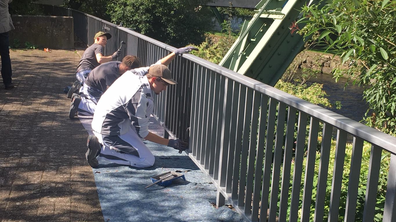 Drei Handwerker arbeiten an einem Geländer am Ufer der Wupper: Die jungen Männer sind Teil einer Ausbildungsinitiative des Wuppertaler Jobcenters.