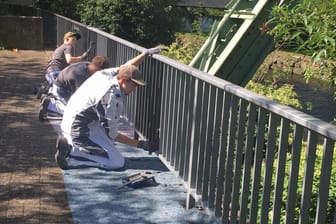 Drei Handwerker arbeiten an einem Geländer am Ufer der Wupper: Die jungen Männer sind Teil einer Ausbildungsinitiative des Wuppertaler Jobcenters.