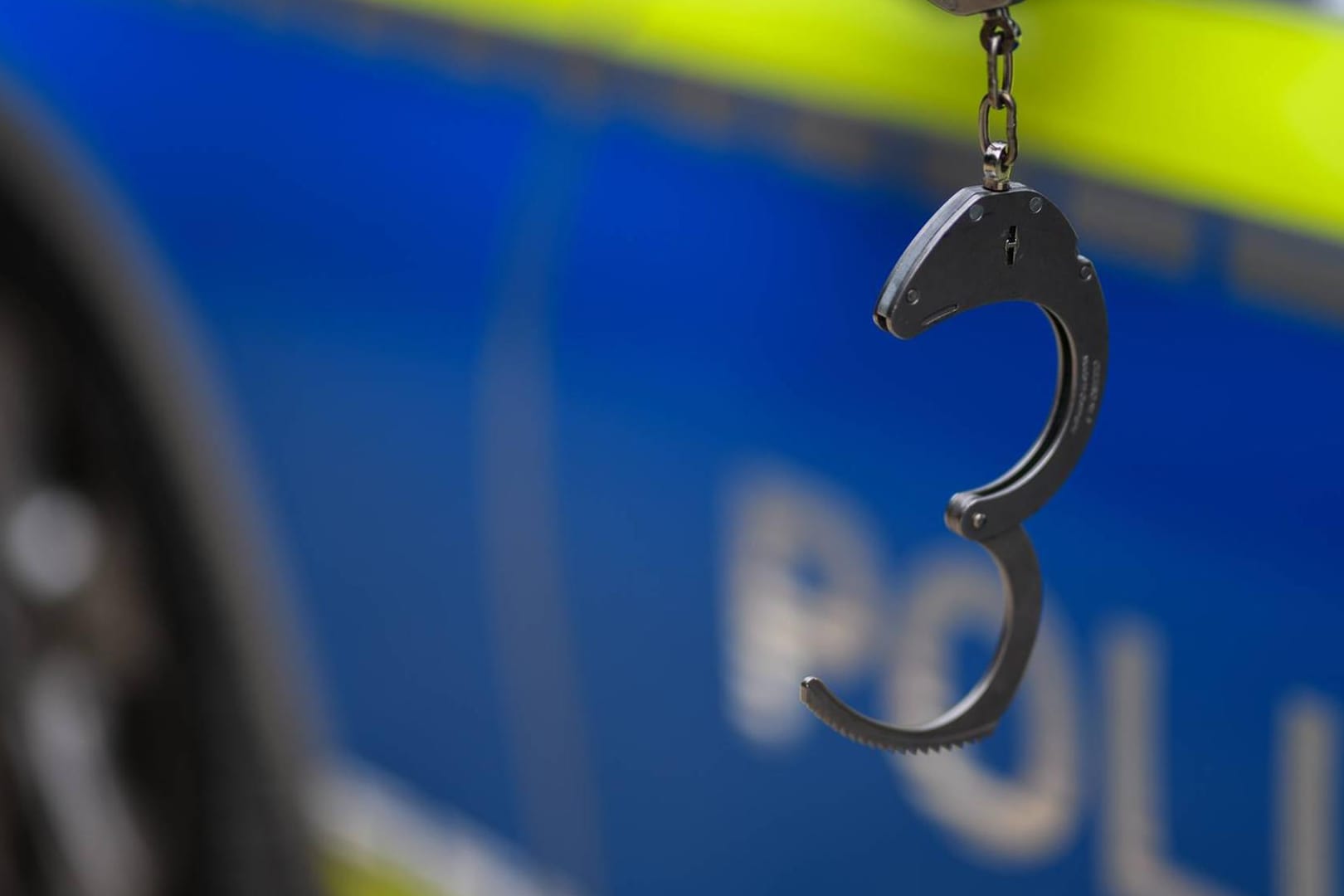 Handschellen vor einem Streifenwagen