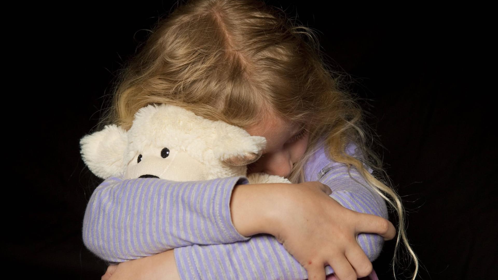 Mädchen umarmt einen Teddy: Ob Kinder vernachlässigt werden, ist oft nicht auf den ersten Blick zu erkennen.