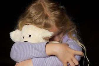 Mädchen umarmt einen Teddy: Ob Kinder vernachlässigt werden, ist oft nicht auf den ersten Blick zu erkennen.