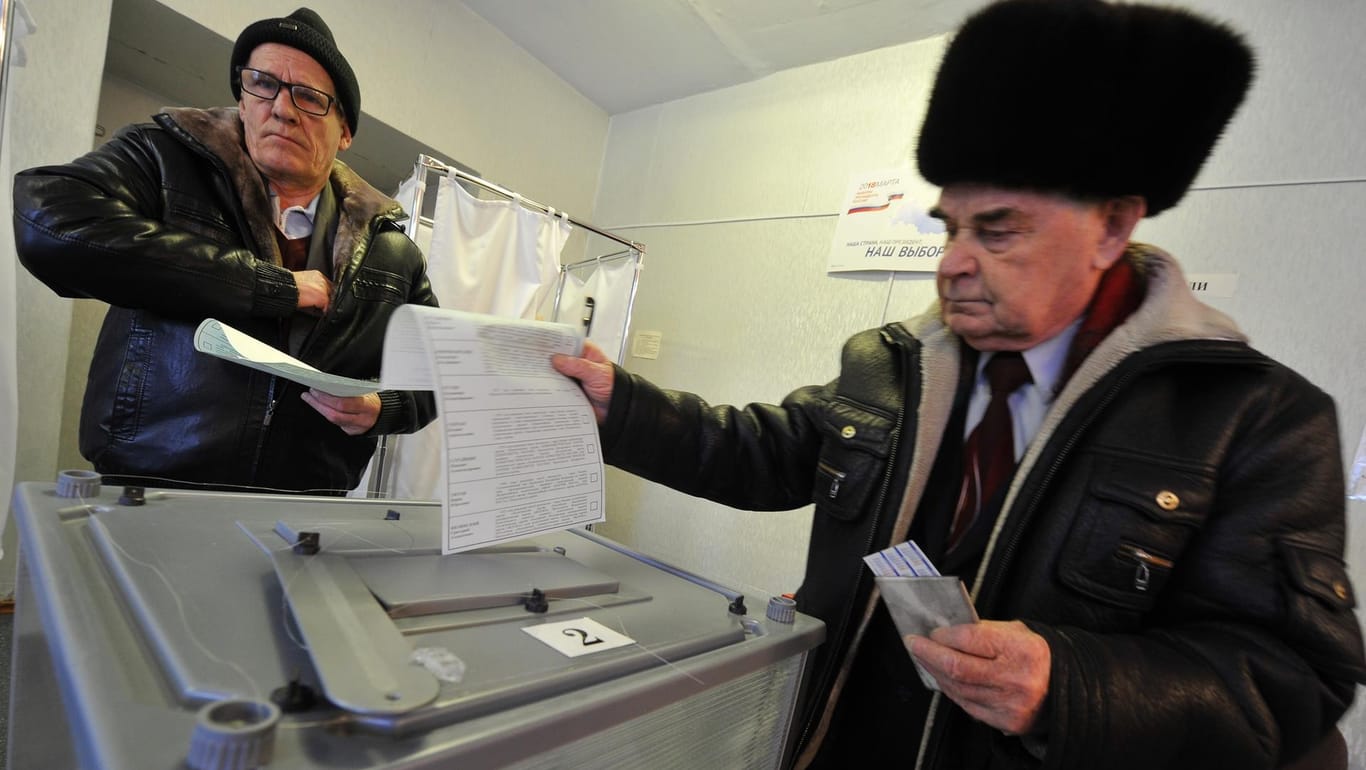 Zwei Männer geben in einem Wahllokal auf der Halbinsel Kamtschatka ihre Stimme ab.