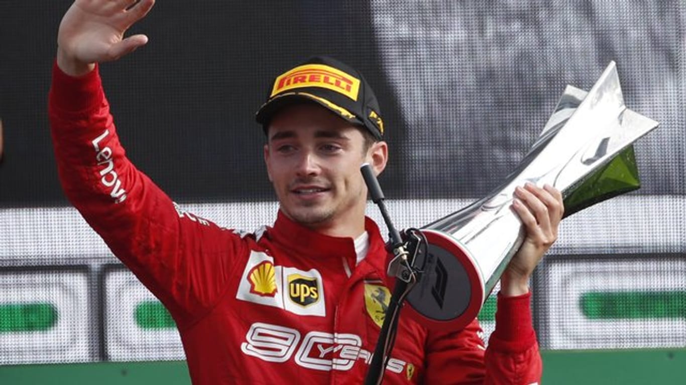 Charles Leclerc vom Team Scuderia Ferrari hält auf dem Podium den Siegerpokal in der Hand.