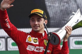 Charles Leclerc vom Team Scuderia Ferrari hält auf dem Podium den Siegerpokal in der Hand.