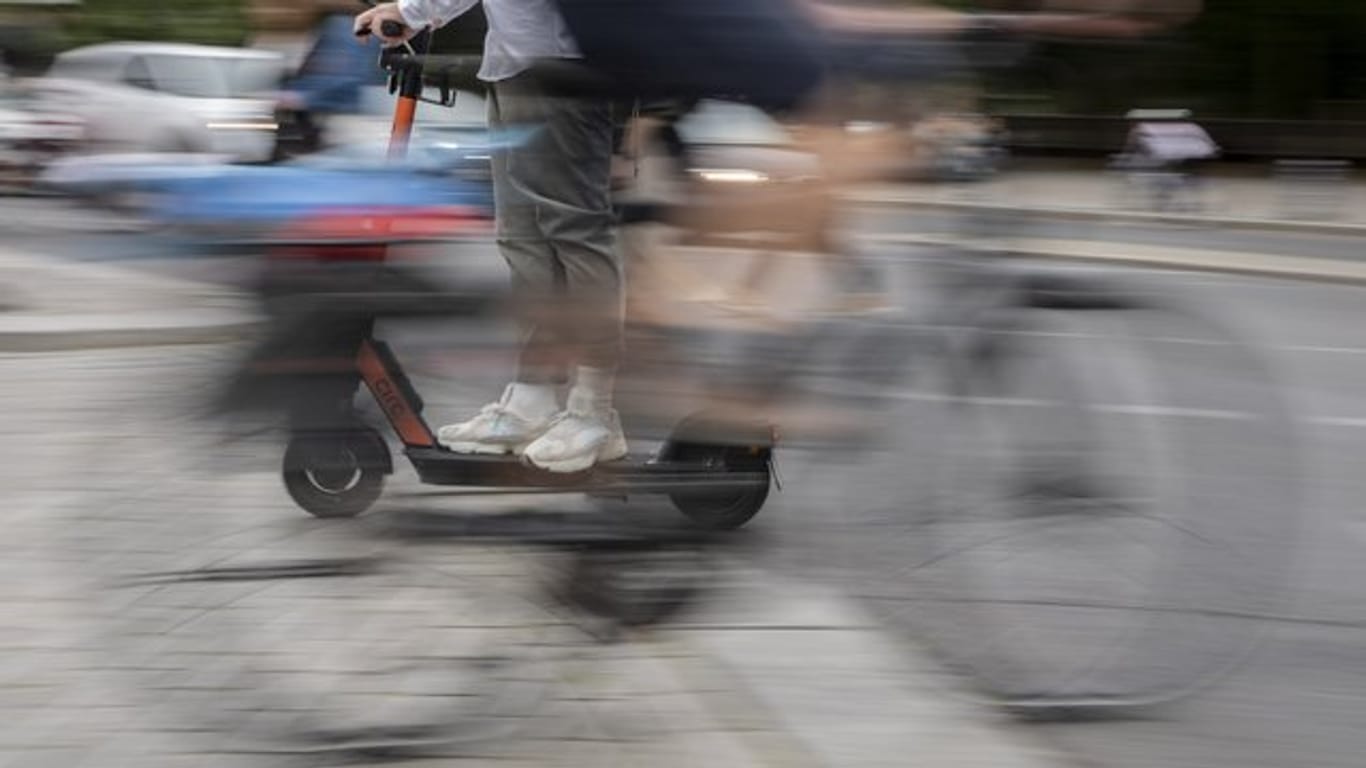 Ein Mann kreuzt mit seinem E-Tretroller einen Fahrradfahrer.