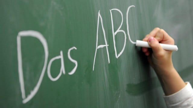 Eine Grundschülerin schreibt das ABC an die Tafel.