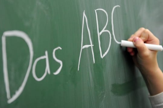 Eine Grundschülerin schreibt das ABC an die Tafel.