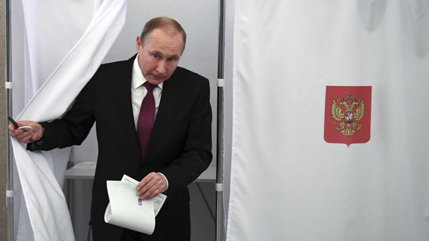 Präsident Wladimir Putin kommt in Moskau aus der Wahlkabine.