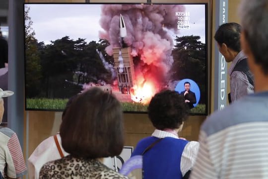 Passanten in Seoul schauen auf einem Fernseher einem Raketenstart Nordkoreas während einer Nachrichtensendung zu.