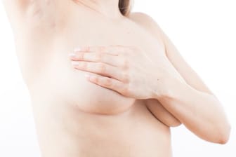 Eine Frau tastete die Brust ab: Beim Gynäkologen erfahren Frauen auch, wie sie ihre Brüste selbst untersuchen können.
