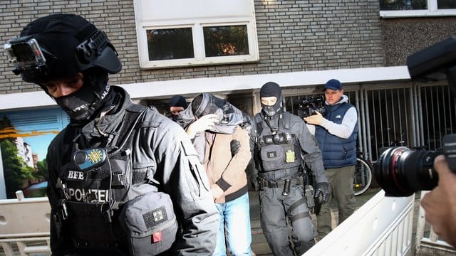 Terror-Razzia in Hamburg: Ein Mann wird von Polizisten aus einem Haus geführt.