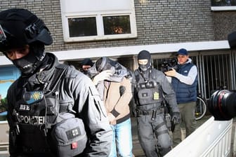 Terror-Razzia in Hamburg: Ein Mann wird von Polizisten aus einem Haus geführt.