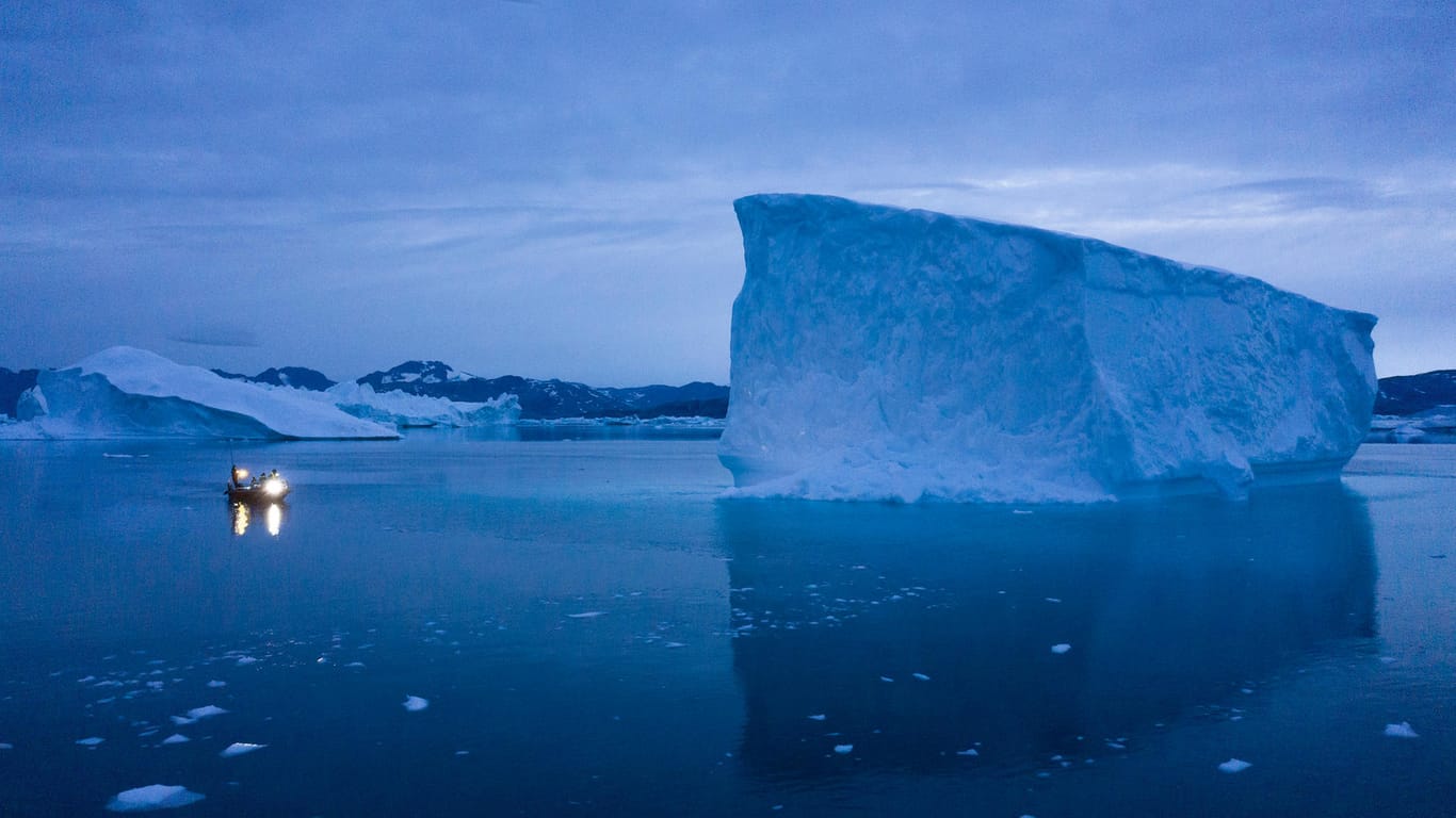 Ein Boot umfährt in der Dämmerung einen Eisberg in Grönland: Nicht nur die Luft lässt das Eis schmelzen – sondern auch das Meerwasser. (Archivbild)