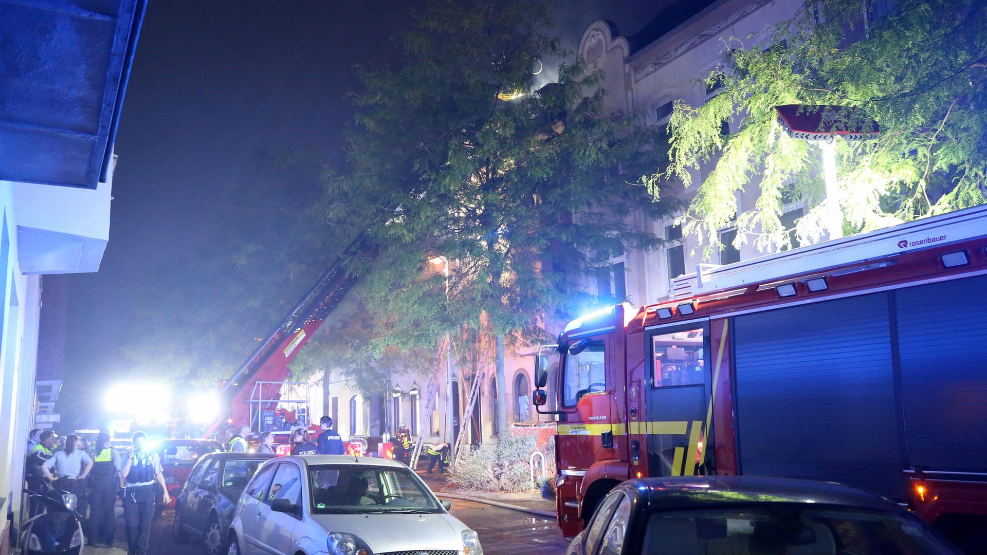 Feuerwehrleute löschen von einem Löschkorb aus den Dachstuhl des brennenden Hauses: Mindestens zwei Menschen sind bei dem Feuer in Krefeld gestorben. Feuerwehrleute löschen von einem Löschkorb aus den Dachstuhl des brennenden Hauses: Mindestens zwei Menschen sind bei dem Feuer in Krefeld gestorben.