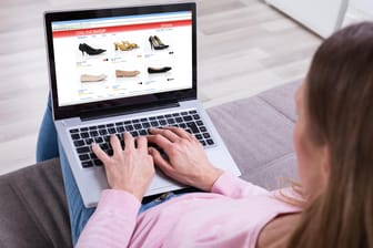 Eine Frau sitzt an ihrem Notebook: Bei unbekannten Onlineshops sollten Verbraucher vor der Bestellung das Impressum prüfen.
