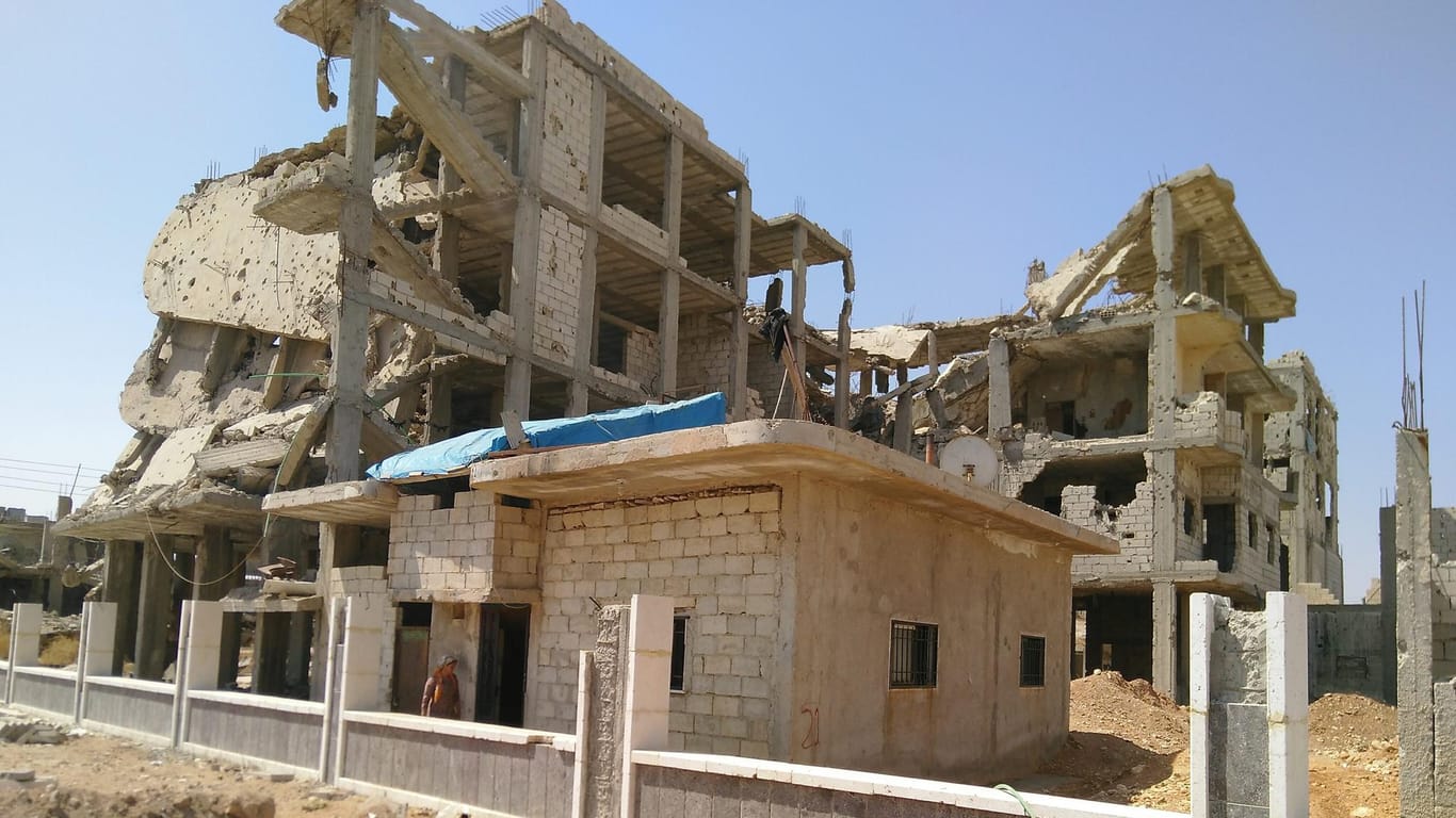 Ruinen in Kobane nah an der Grenze zur Türkei: Im Vordergrund wird eine Mauer errichtet. Die Ruinen sollen als Mahnmal gegen den Krieg erhalten bleiben.