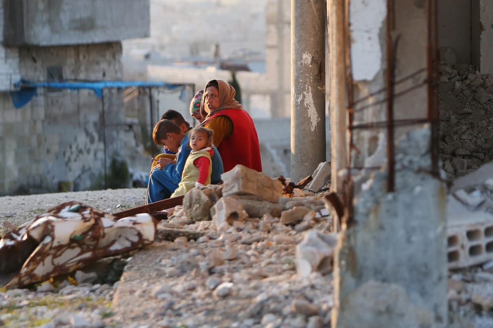 Frau mit Kindern in einem zerstörten Haus in Kobane: In der Stadt ist trotz der Kriegsverwüstungen viel Neues entstanden.