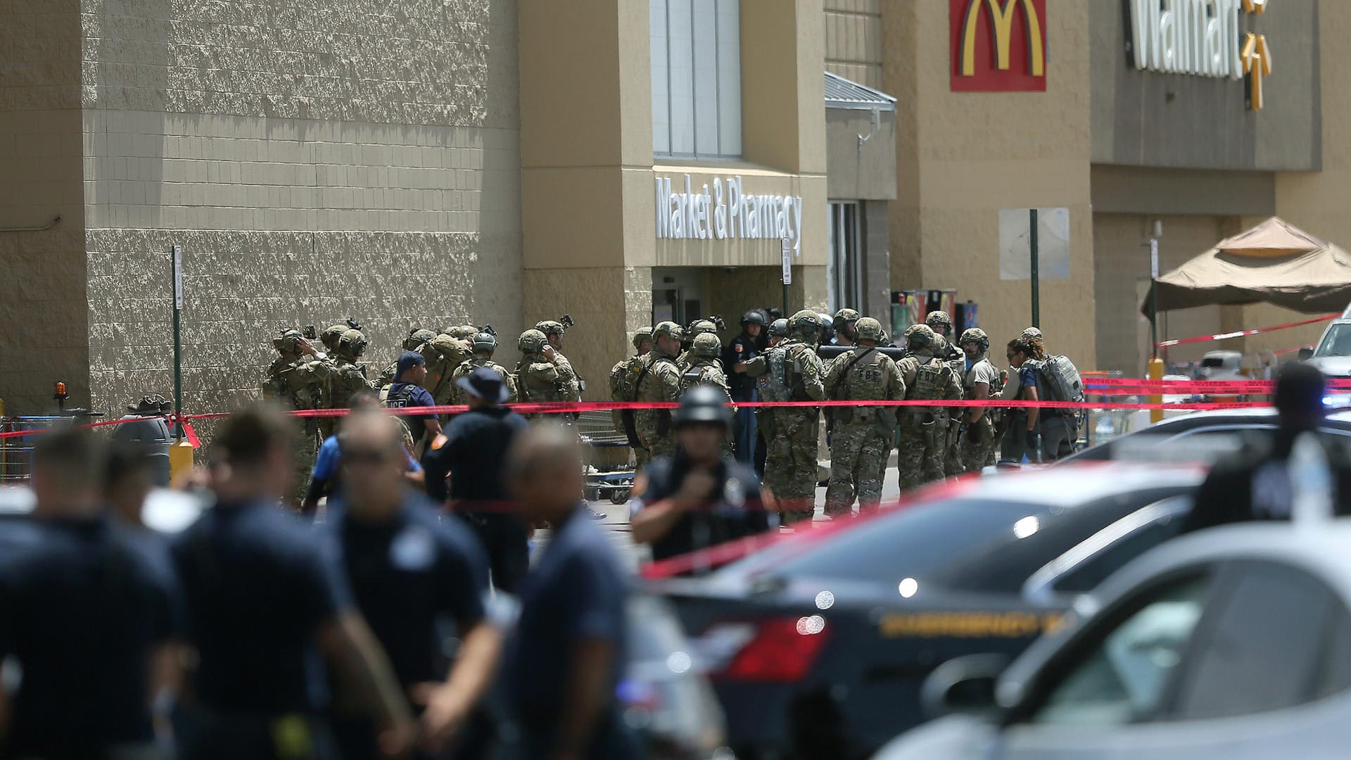 USA, El Paso: Mitglieder einer Spezialeinheit und Polizisten stehen vor dem Eingang eines Ladenkomplexes, in dem ein Mann zahlreiche Menschen erschossen hat USA, El Paso: Mitglieder einer Spezialeinheit und Polizisten stehen vor dem Eingang eines Ladenkomplexes, in dem ein Mann zahlreiche Menschen erschossen hat