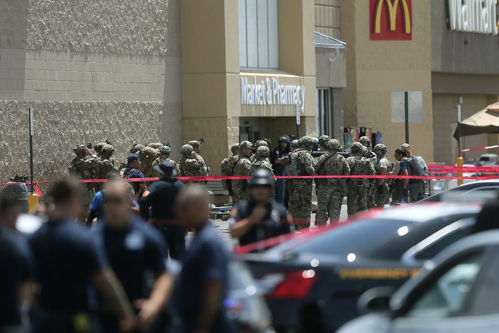 USA, El Paso: Mitglieder einer Spezialeinheit und Polizisten stehen vor dem Eingang eines Ladenkomplexes, in dem ein Mann zahlreiche Menschen erschossen hat